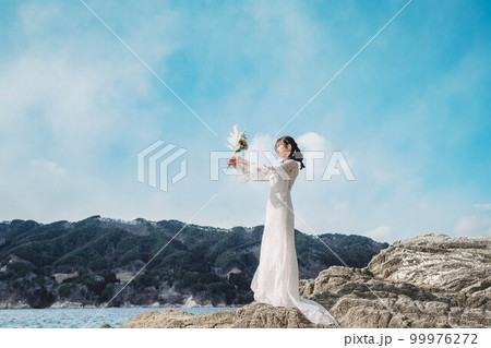 岩場に立つ白いドレスを着た女性の写真素材 [99976272] - PIXTA