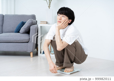 体重を計ってショックを受ける男性 99982011