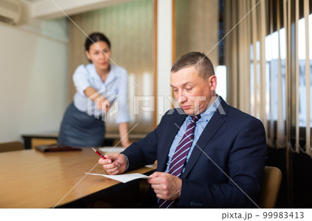 Shocked office employe reading papers with dissatisfied female manager Shocked office employe reading papers with dissatisfied female manager 99983413