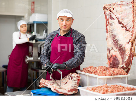 Adult male butcher sawing beef ribs 99983603