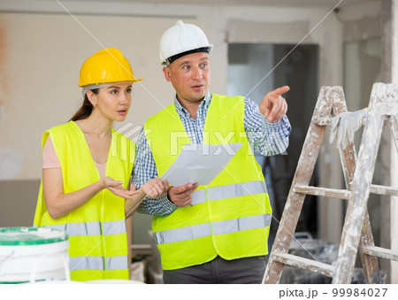 Man and woman builders talking in house 99984027