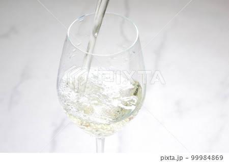 よく冷えた白ワインを白ワイン用のワイングラスに注ぐ 99984869