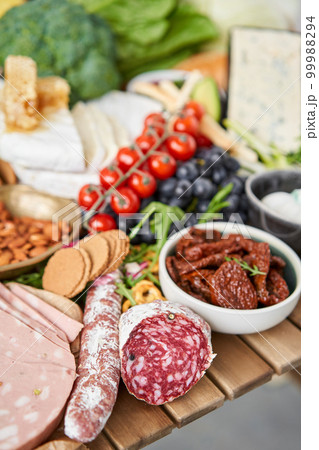 Salami sausage close-up. Table full of mediterranean appetizers, tapas or antipasto. Assorted Italian food set. Delicious snack on party or picnic time. Meat and cheese. Italian style banquet.  99988294