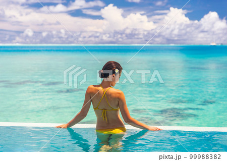 Wellness spa healthy body care woman relaxing in infinity swimming pool at luxury resort pampering summer getaway vacation travel background lifestyle 99988382