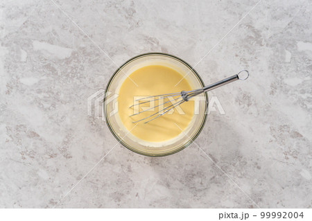 Flat lay. Mixing ingredients in a glass mixing bowl to bake funfettti bundt cake. 99992004