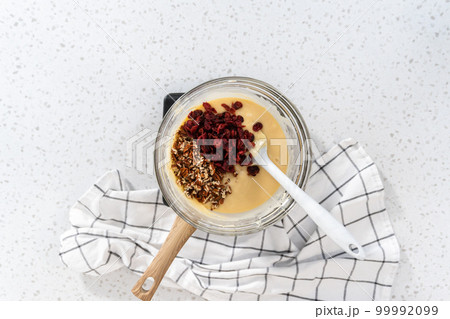 Flat lay. Melting white chocolate chips and other ingredients in a glass mixing bowl over boiling water to prepare white chocolate cranberry pecan fudge. Flat lay. Melting white chocolate chips and other ingredients in a glass mixing bowl over boiling water to prepare white chocolate cranberry pecan fudge. 99992099