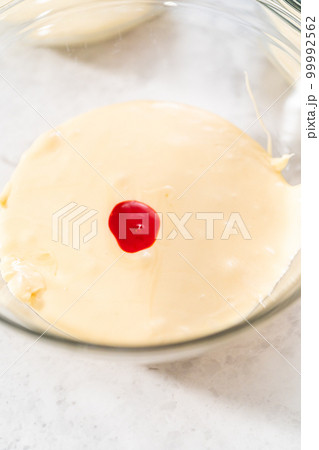 Mixing in orange and yellow food coloring into melted chocolate to prepare candy corn fudge. 99992562