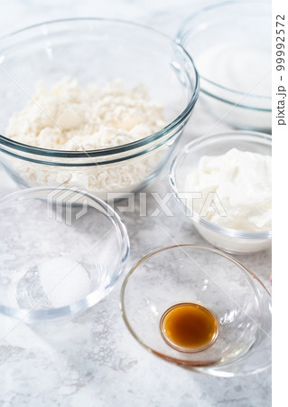 Ingredients in glass mixing bowls to bake funfettti bundt cake. 99992572