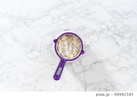 Flat lay. Melting chocolate chips in a candy melting pot to make red, white, and blue chocolate-covered pretzel twists. 99992585