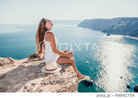 Digital nomad, Business woman working on laptop by the sea. Pretty lady typing on computer by the sea at sunset, makes a business transaction online from a distance. Freelance, remote work on vacation Digital nomad, Business woman working on laptop by the sea. Pretty lady typing on computer by the sea at sunset, makes a business transaction online from a distance. Freelance, remote work on vacation 99992709
