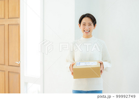 玄関で段ボールを持つ女性 99992749
