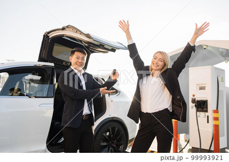 Cheerful woman receiving keys from her new electric car 99993921