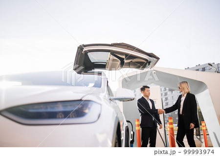 Dealer shaking hands with female client during car purchase 99993974