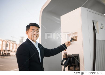 Businessman paying with card for charging electro car 99994635