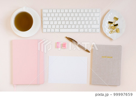 Office desk, notebooks, keyboard and colored pencils, a cup of tea, mimosa flowers on a beige background. Minimal business concept for women. 99997659