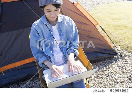 テント前でノートパソコンを使う若い女性 ワーケーションイメージ テント前でノートパソコンを使う若い女性 ワーケーションイメージ 99998665