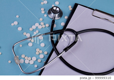 Close up stethoscope with clipboard and white pills. Blank paper for copy space. 99999310