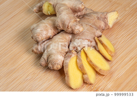 Fresh whole ginger root on wooden background close up. Spices and herbs seasoning for cooking. Medicinal herbs. Use of slice ginger in aromatherapy. High content of essential oils in the plant Fresh whole ginger root on wooden background close up. Spices and herbs seasoning for cooking. Medicinal herbs. Use of slice ginger in aromatherapy. High content of essential oils in the plant 99999533