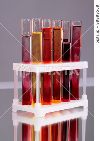 Vertical shot of colorful laboratory test tubes with blood. Reflective surface with gray background. Vertical shot of colorful laboratory test tubes with blood. Reflective surface with gray background. 99999569