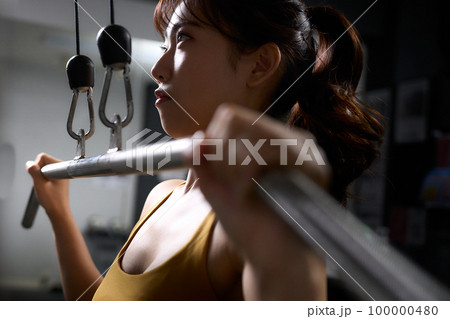 トレーニングマシーンを使って筋トレをする若い女性 トレーニングマシーンを使って筋トレをする若い女性 100000480