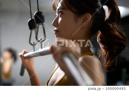 トレーニングマシーンを使って筋トレをする若い女性 トレーニングマシーンを使って筋トレをする若い女性 100000483