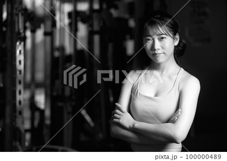 腕組みのポーズをとるスポーツウェア姿の若い女性　モノクロイメージ 100000489