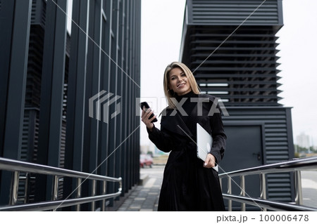 a business woman holds a phone in her hand and speaks with a partner on a cellular connection 100006478