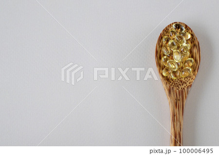 Sunny vitamin D3 supplement capsules in a wooden spoon beige background. Blank space for copying or text. Pills, medications and vitamins. Close-up. Sunny vitamin D3 supplement capsules in a wooden spoon beige background. Blank space for copying or text. Pills, medications and vitamins. Close-up. 100006495