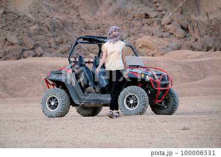 Young woman was riding a buggy. Walks away from him in the desert and looks away. 100006531