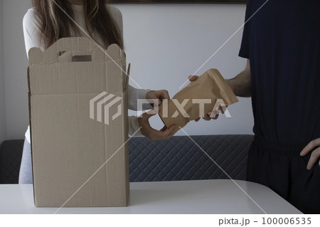 A woman hands a man food from a box. Unpacking an edible parcel. 100006535