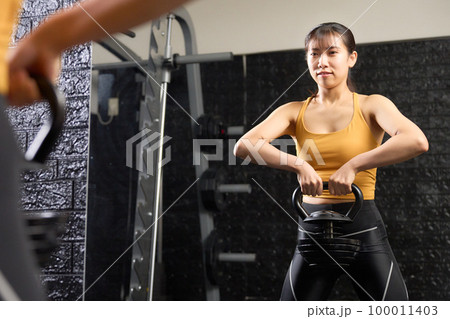 ケトルベルを使ってトレーニングをする若い女性 100011403