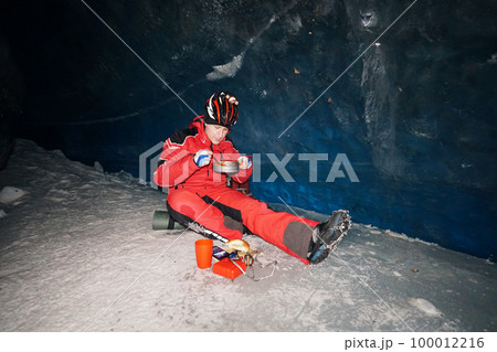 A mountaineer caver eats in a deep ice cave A mountaineer caver eats in a deep ice cave 100012216