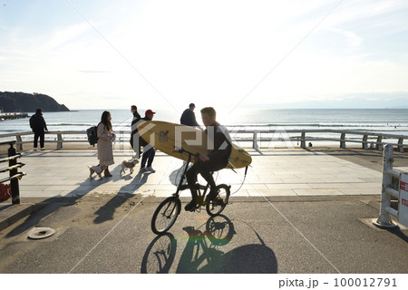 自転車で片瀬西浜遊歩道を移動するサーファー 100012791