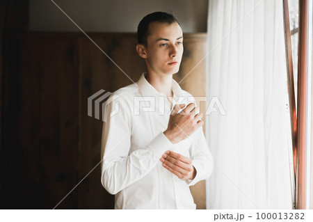Grooms morning preparation. Handsome man getting dressed and preparing for the wedding 100013282