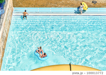 People relax on inflatable rubber rings in swimming pool with clear blue water. Fun activities in water park at summer resort upper view People relax on inflatable rubber rings in swimming pool with clear blue water. Fun activities in water park at summer resort upper view 100013772