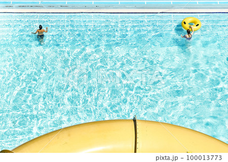 People relax on inflatable rubber rings in swimming pool with clear blue water. Fun activities in water park at summer resort upper view 100013773