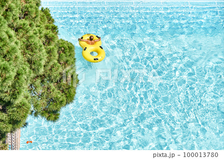Man relax on inflatable rubber rings in swimming pool with clear blue water. Fun activities in water park at summer resort upper view Man relax on inflatable rubber rings in swimming pool with clear blue water. Fun activities in water park at summer resort upper view 100013780