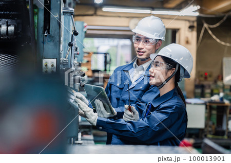 タブレット端末を確認しながら働く技術スタッフ 100013901