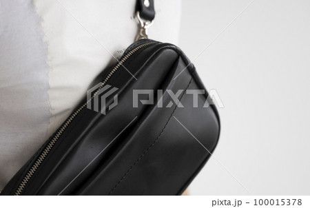 Details of leather black handmade bag over his shoulder. Dark designer banana bag. Comfortable small bag for walking. Details of leather black handmade bag over his shoulder. Dark designer banana bag. Comfortable small bag for walking. 100015378