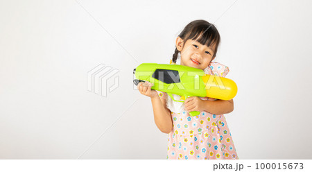 Happy Songkran Day, Asian little girl holding plastic water gun, Thai child funny hold toy water pistol and smile, isolated on white background, Thailand Songkran festival national culture concept 100015673