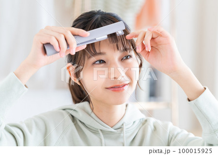 ヘアアイロンをする若い女性 100015925
