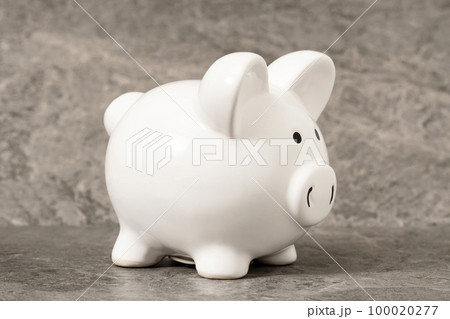 White piggy bank on a grey stone background 100020277