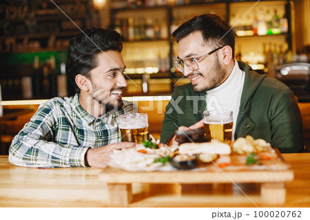 Indian friends celebrating in a pub with beer Indian friends celebrating in a pub with beer 100020762