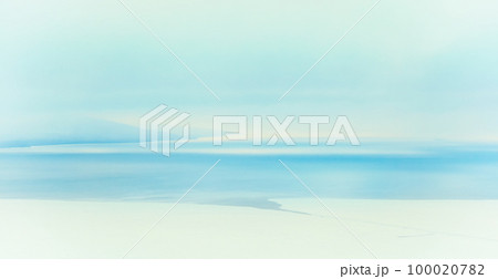 Blurry winter snow background. Winter seascape. Icy shore and ice-covered sea bay. Freezing water. Snow and ice on the coast. Mountains in the distance. 100020782