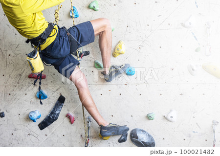 Close up view of young man or climber feet in climbing shoes on artificial indoor wall at the climbing center, sport activity concept Close up view of young man or climber feet in climbing shoes on artificial indoor wall at the climbing center, sport activity concept 100021482