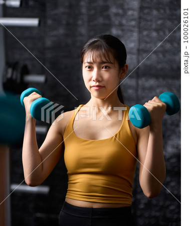 鏡の前でダンベルを使ってトレーニングをする若い女性 鏡の前でダンベルを使ってトレーニングをする若い女性 100026101