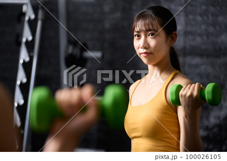 ダンベルを使ってトレーニングをする若い女性 100026105