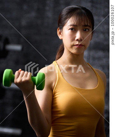 ダンベルを使ってトレーニングをする若い女性 ダンベルを使ってトレーニングをする若い女性 100026107