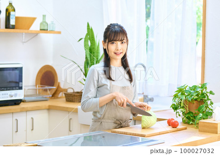 キッチンで料理するエプロン姿の若い主婦 100027032