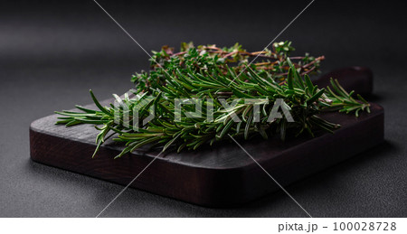 Sprigs of fresh green rosemary on a wooden cutting board Sprigs of fresh green rosemary on a wooden cutting board 100028728